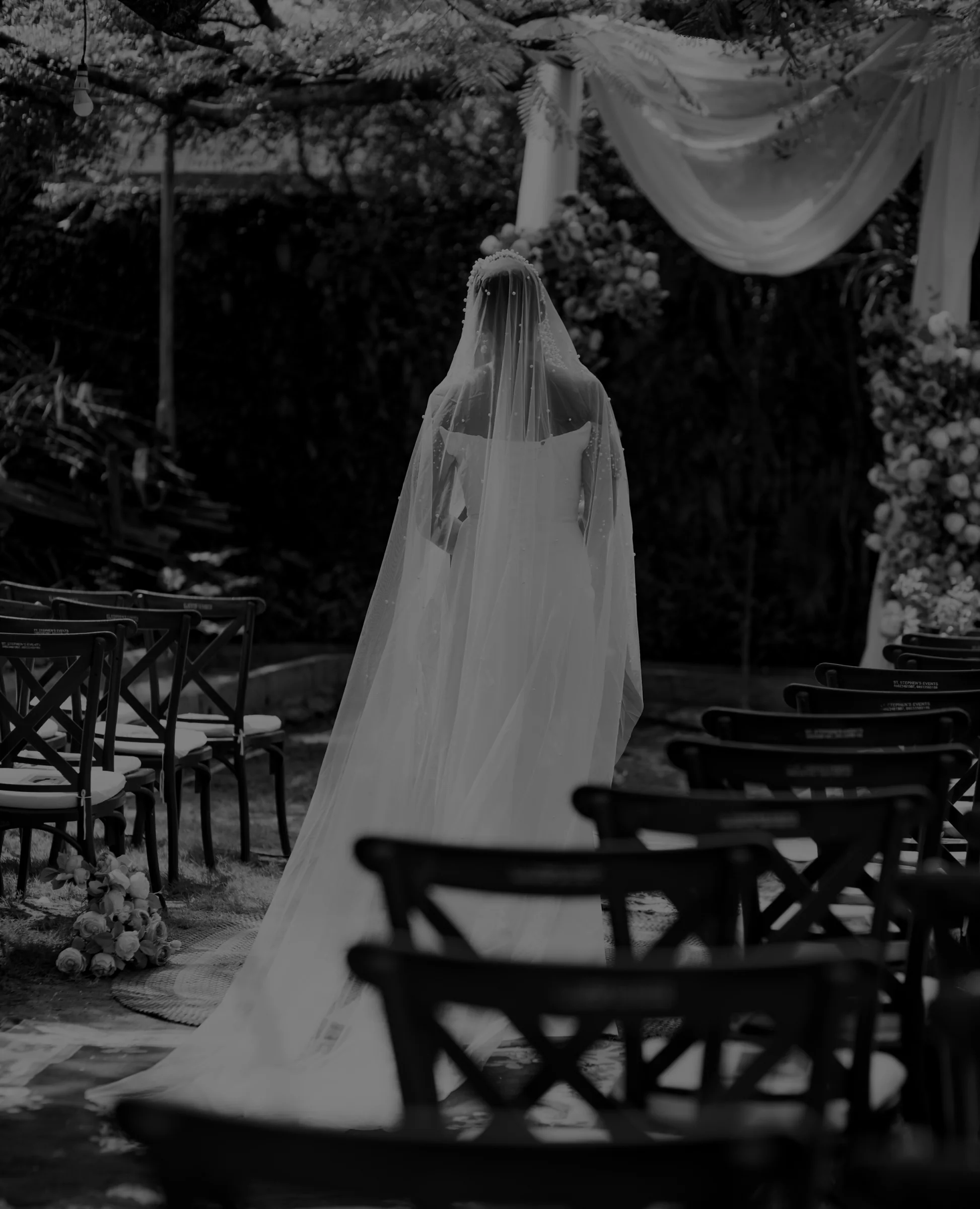 Bride in a pearl-scattered cathedral veil walking a garden aisle